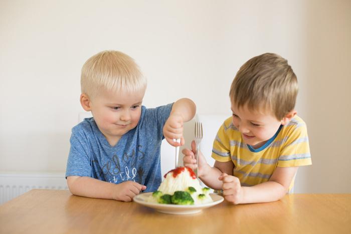 2 children eating mashed potato volcanoes with fork
